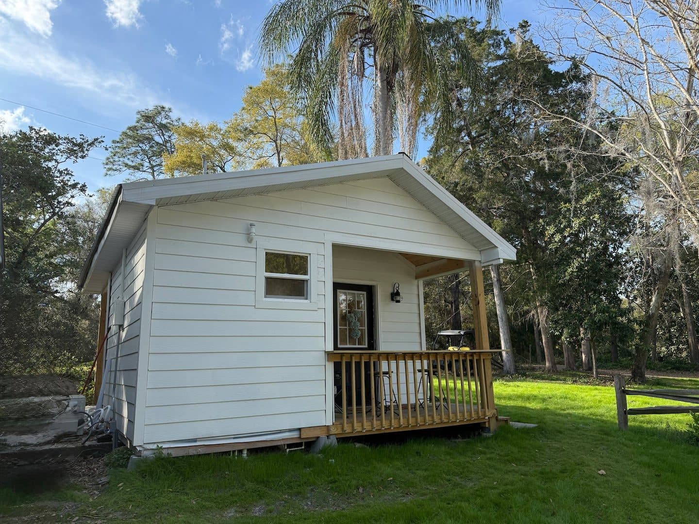 White cabin with a small front porch on a grassy lawn