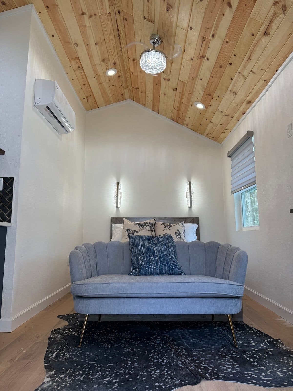 Loveseat at the foot of the bed beneath a vaulted wood ceiling