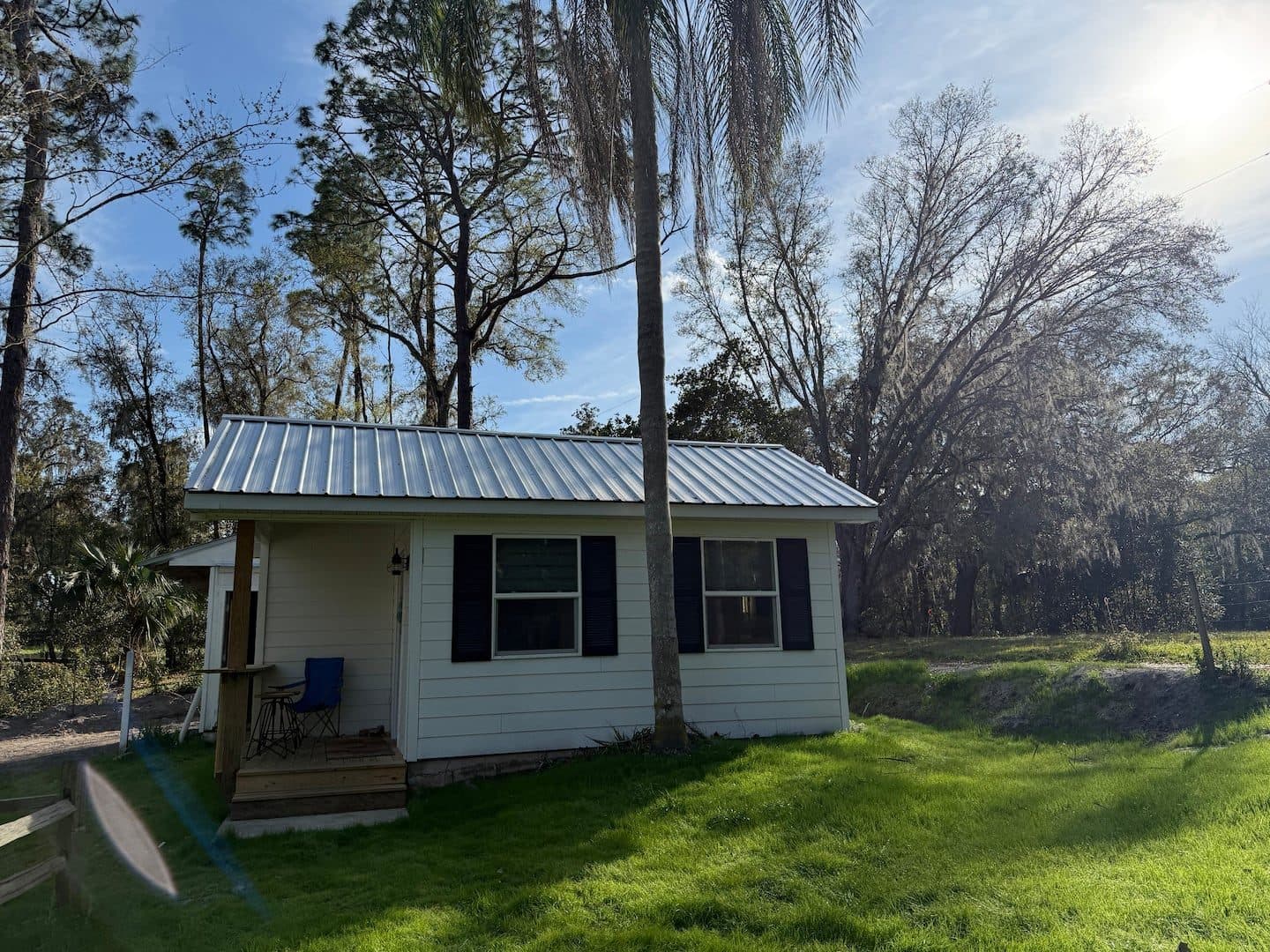 Small building with a metal roof and a porch among the trees