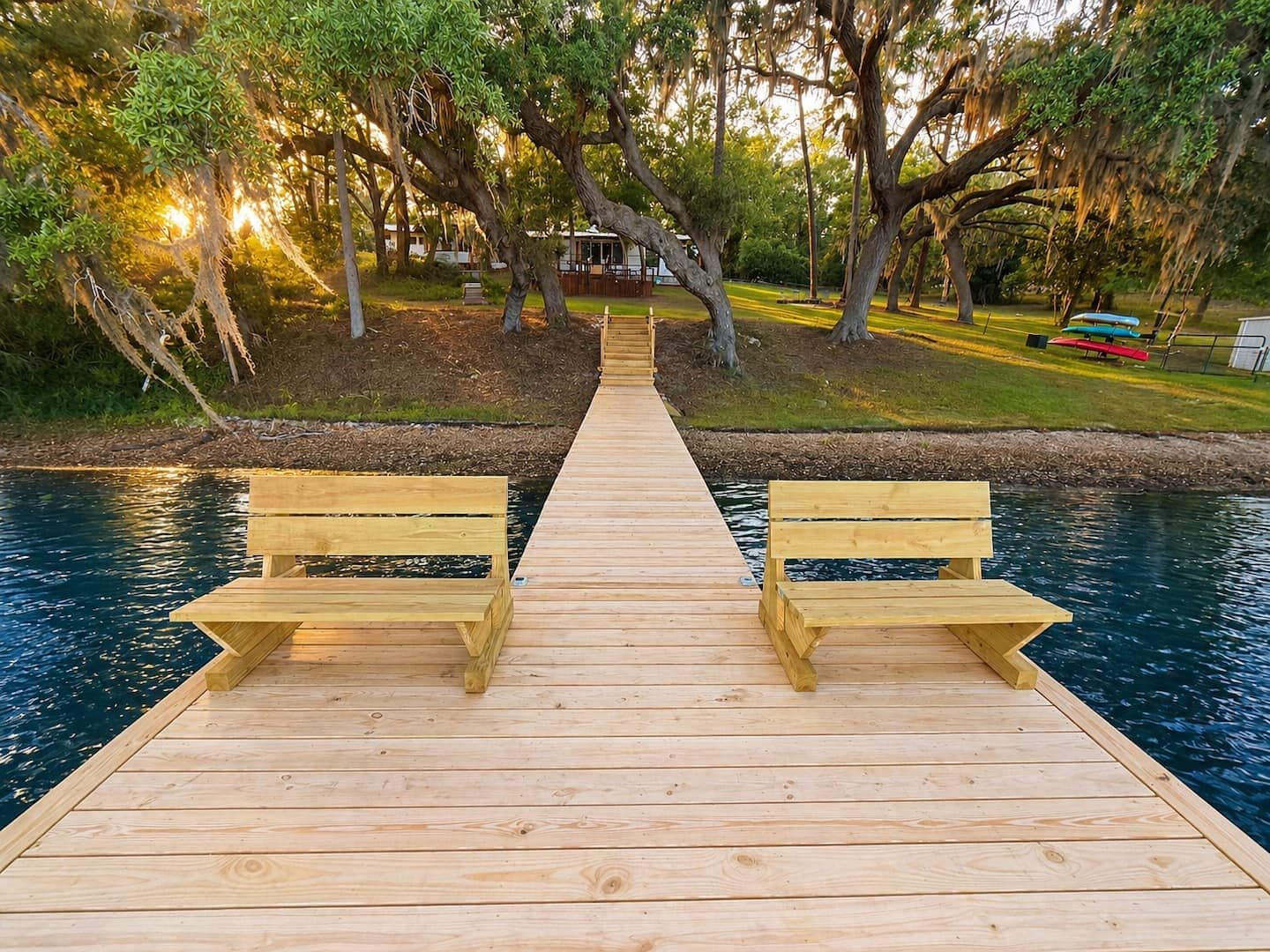 Wooden dock with two benches on the lake at sunset